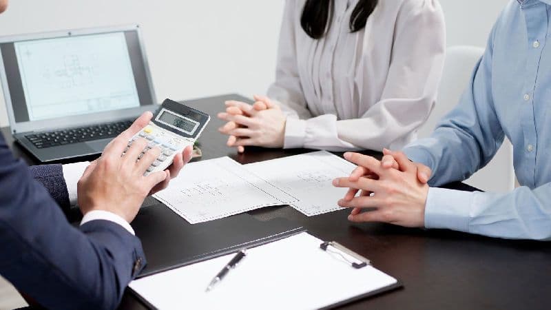 Corretor e casal de compradores analisam as certidões para compra de imóvel e valores.