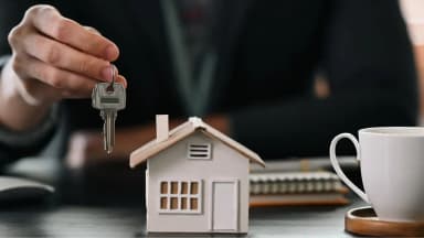 Corretor entregando chave residencial durante feirão de imóveis com foco em compra, financiamento e negociação imobiliária.