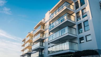 Fachada de prédio moderno de luxo exemplificando a tipologia de apartamentos com varandas de vidro.