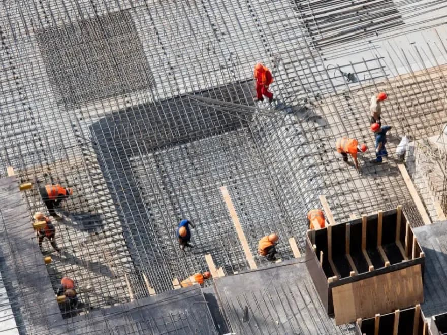 Vista aérea de operários montando a malha de vergalhões em uma laje de concreto armado.