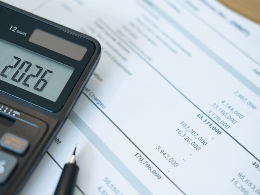 Papelada com valores e calculadora sob a mesa.