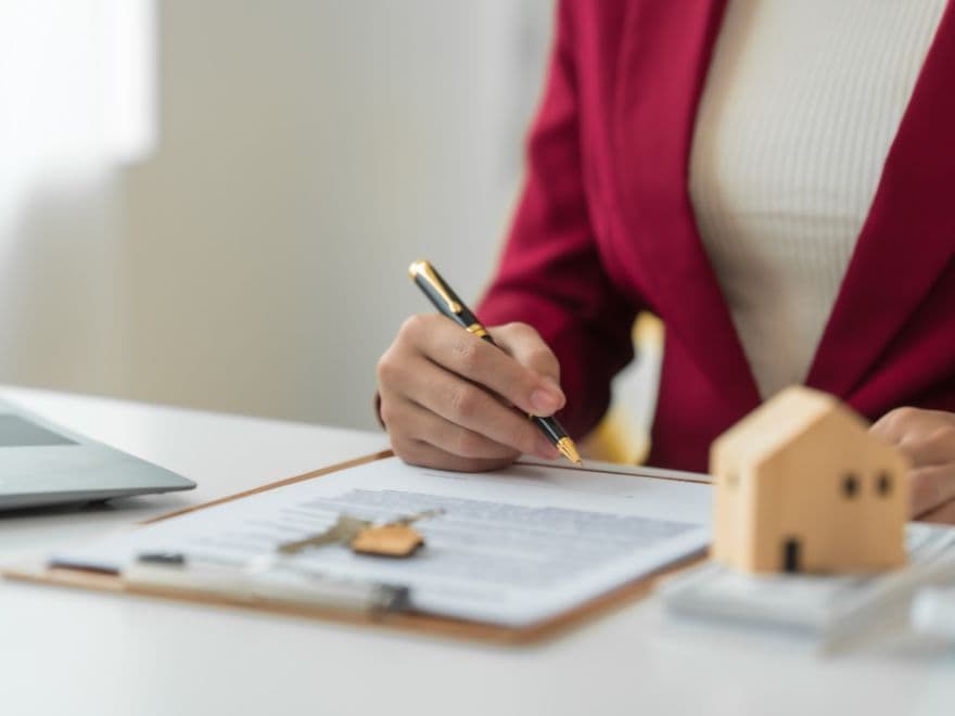 Mulher de terno bordô assinalando com caneta na certidão o que aparece nela.